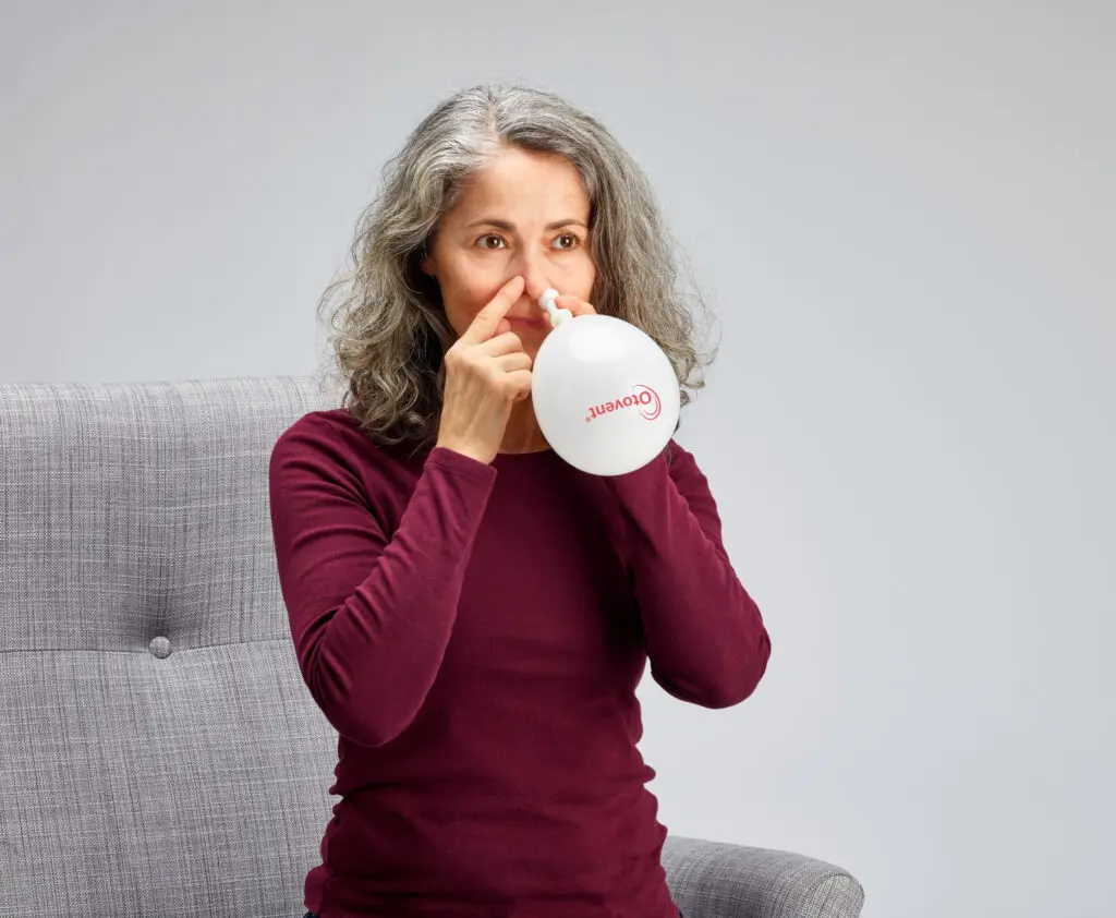 Vrouw gebruikt een Otovent-ballon om de oren te klaren